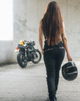 A woman walks towards her motorcycle wearing black women's motorcycle jeans from Moto Girl