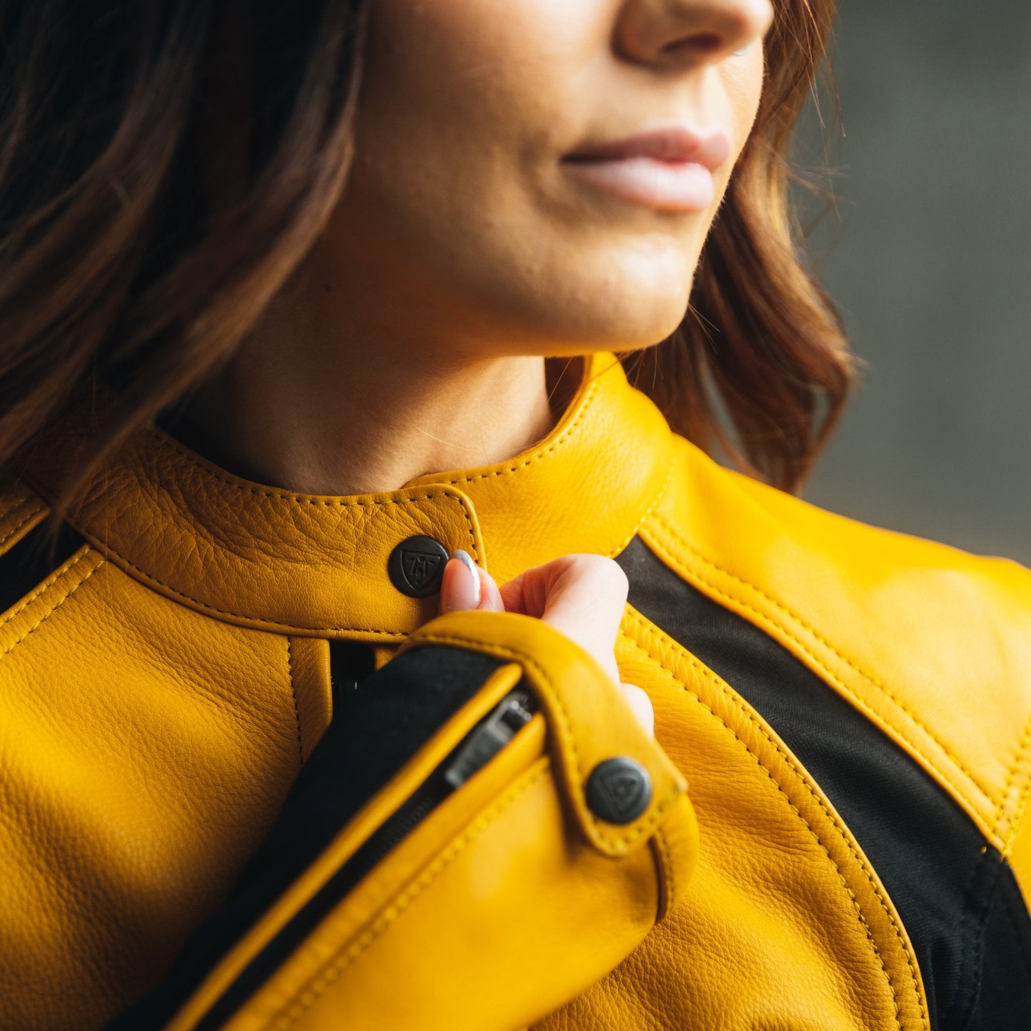 Close-up of a woman zipping up her yellow black motorcycle jacket.