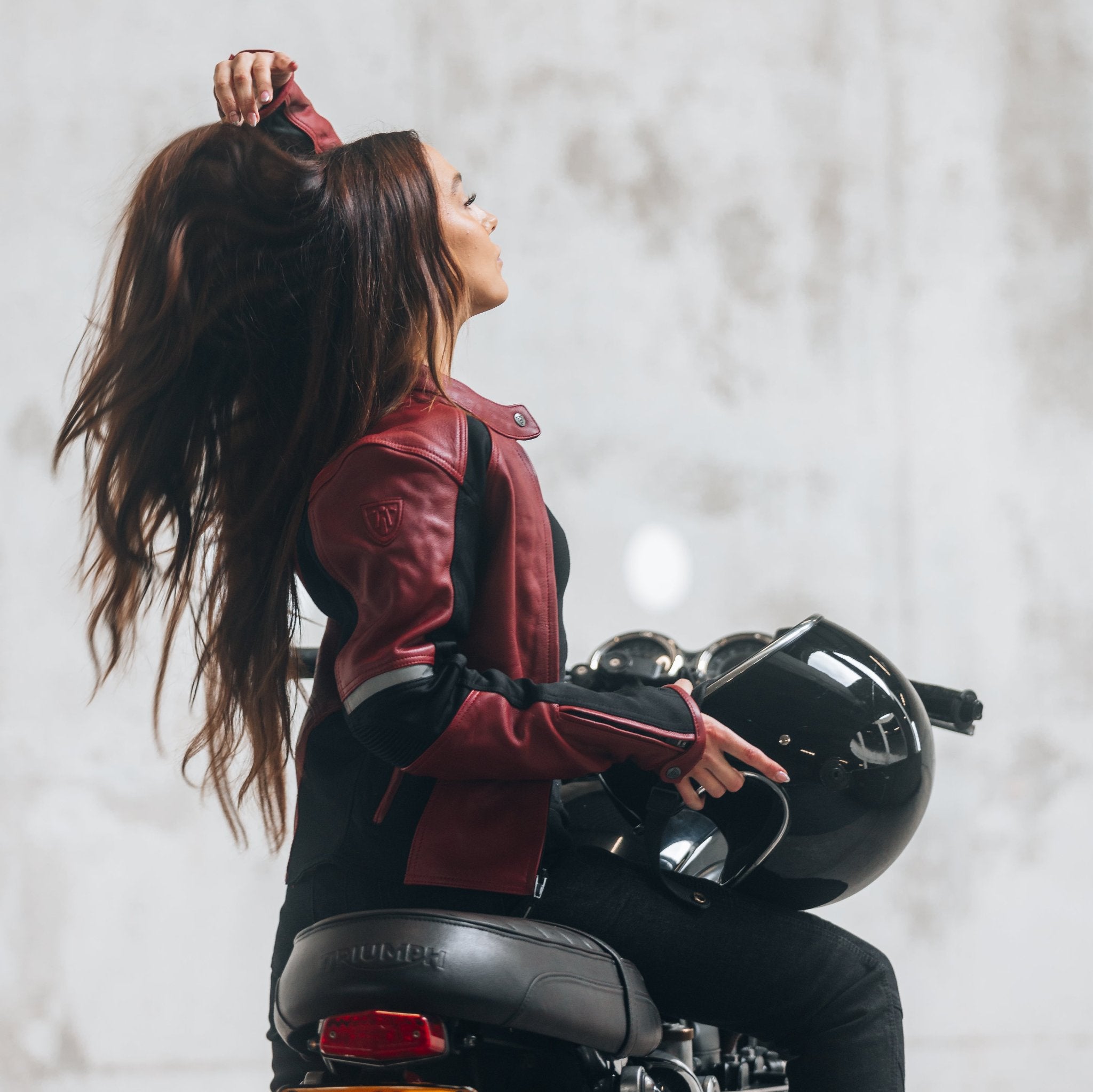 
A young woman on her motorcycle wearing a red and black women&#39;s motorcycle jacket with reflectors on the sleeves.