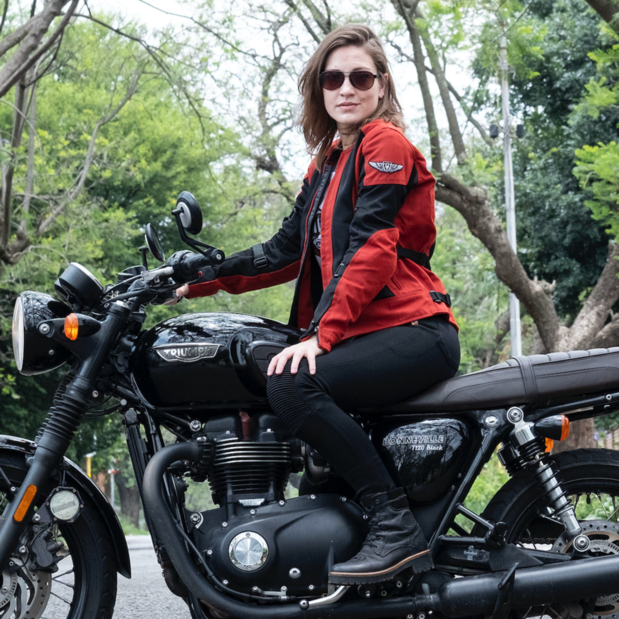 a young woman on a Triumph motorcycle wearing red and black women&#39;s motorcycle summer jacket from Moto Girl 